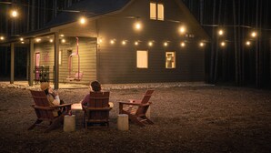 Een houten vakantiehuis met lichtslingers, een overdekte veranda en buiten zitplaatsen.