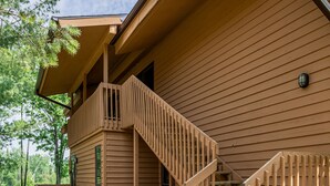 A wooden cabin with a wooden staircase leading to a balcony. - Northern Michigan paradise!  sleeps 7 KING bed. Private association outdoor pool (Mancelona)
