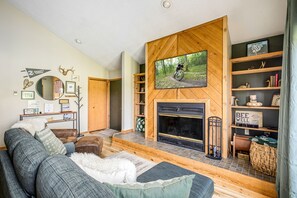 Una sala de estar acogedora con chimenea, televisor montado y estantería.