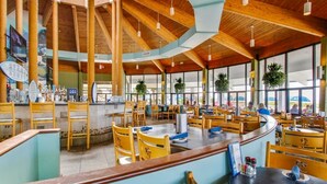 Un restaurante espacioso con techos altos, vigas de madera y grandes ventanales.