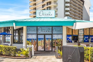 A restaurant named 'Oceans bar & grill' with a turquoise awning, outdoor seating, and a view of the ocean through the entrance. - Edgewater Resort Tower 1 Fabulous Pool and Beach Views (Panama City Beach)