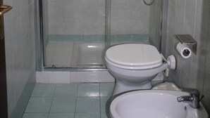A bathroom with a glass-enclosed shower, a toilet, and a sink. - Triple Room (Roma)