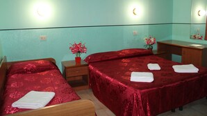 A hotel room with two beds, a wooden desk, a mirror, and a vase of flowers. - Triple Room (Roma)