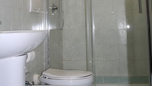 A bathroom with two toilets, a sink, and a glass-enclosed shower area. - Triple Room (Roma)
