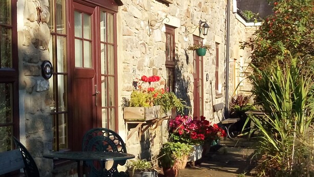 A stone building with a wooden door and windows, outdoor seating, and potted plants. - Gorgeous cottage in rural idyl, sleeps 4 (Newcastle-upon-Tyne)