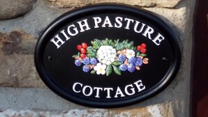 A black metal sign with "HIGH PASTURE COTTAGE" written on it, surrounded by colorful grape illustrations. - Gorgeous cottage in rural idyl, sleeps 4 (Newcastle-upon-Tyne)
