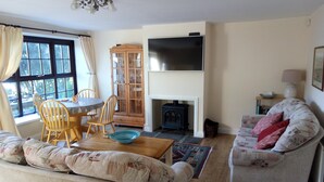 A living room with a sofa, a dining table with chairs, a TV, a fireplace, and a window with curtains. - Gorgeous cottage in rural idyl, sleeps 4 (Newcastle-upon-Tyne)