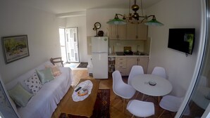 Ein kompakter Wohnraum mit Küchenzeile, Essbereich und Sofa.