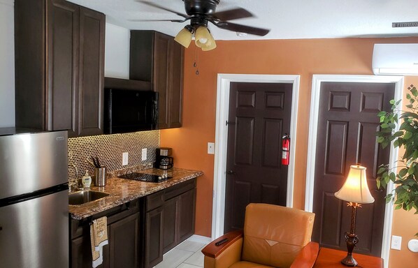A kitchen with dark wooden cabinets, a stainless steel refrigerator, a granite countertop, and a ceiling fan. - TAMPA SUITE 4 Minutes from SEMINOLE HARD ROCK CASINO (Tampa)