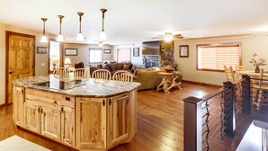 A spacious kitchen with a central island, wooden cabinets, and pendant lighting. - Modern Deadwood Apt with Mountain Views & Grill! (Deadwood)