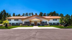 A large, two-story building with a symmetrical facade, a central entrance with a door and windows, and a stone foundation. - Modern Deadwood Apt with Mountain Views & Grill! (Deadwood)