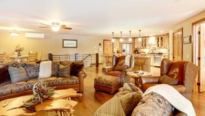 A spacious living room with a sofa, ottoman, and armchair, a wooden coffee table, and a dining area with a table and chairs. - Modern Deadwood Apt with Mountain Views & Grill! (Deadwood)