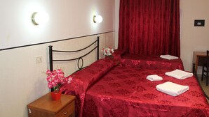 Una habitación de hotel con una cama, una mesita de noche, un escritorio y una cortina roja.