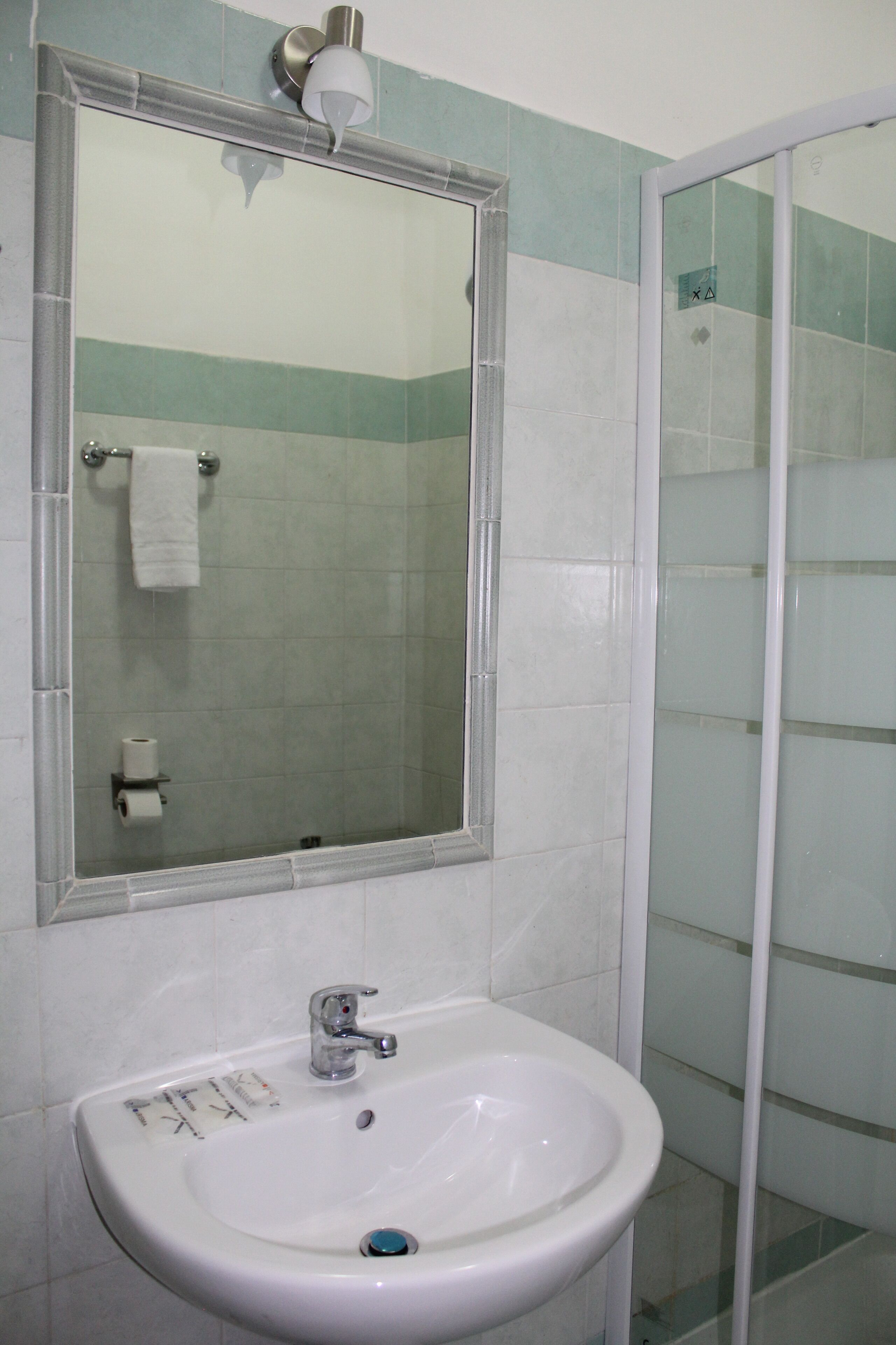 A bathroom with a white sink, a mirror, and a glass shower enclosure.