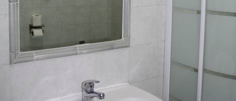 A bathroom with a white sink, a mirror, and a glass shower enclosure.