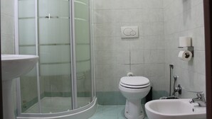 Un baño con ducha de vidrio, inodoro y lavamanos.