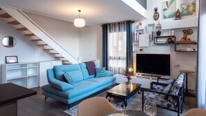 Ein modernes Wohnzimmer mit einem blauen Sofa, einem Couchtisch, einem Fernseher und einer Treppe.