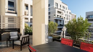 Eine Dachterrasse mit Sitzgelegenheiten im Freien, Blick auf moderne Gebäude und einem klaren Himmel.