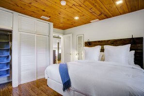 A bedroom with a wooden ceiling, a bed with white bedding, a blue throw, and a wooden headboard. - Bungalow Reborn: Pool, Sonos, Fire Pit Oasis! (Fort Lauderdale)
