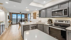 A modern kitchen with grey cabinets, a large island, a microwave, an oven, and a coffee maker.
