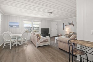Relax in this stylish living area with a dining table, sofa, and TV, offering a view of the outside.