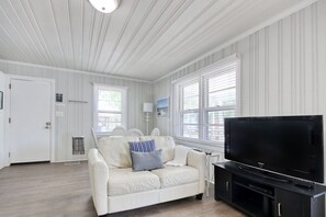 Relax in this stylish living room with a large flat-screen TV, comfortable sofa, and beautiful window views.