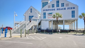 Un edifici blanc amb la indicació "SURFSIDE BEACH PIER", una escala i una palmera.