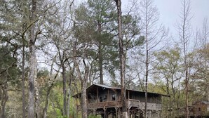 A rustic cabin with a wooden deck and a small stream in front. - Skip’s Rustic River Cabin near Okefenokee Swamp (Folkston)