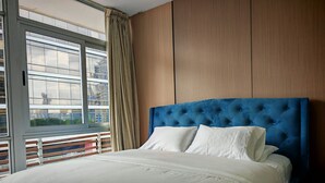 A bedroom with a large bed, a view through a window, and a wooden wall. - Lovely Modern Apartment Two Bedrooms, Two Bathrooms, Nice Location (Panamá)