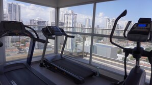 A gym with treadmills and exercise bikes, large windows with a city view. - Lovely Modern Apartment Two Bedrooms, Two Bathrooms, Nice Location (Panamá)