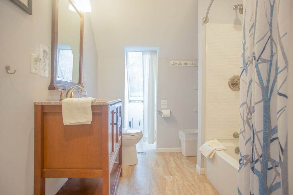 A bathroom with a wooden vanity, a mirror, a toilet, and a shower area.