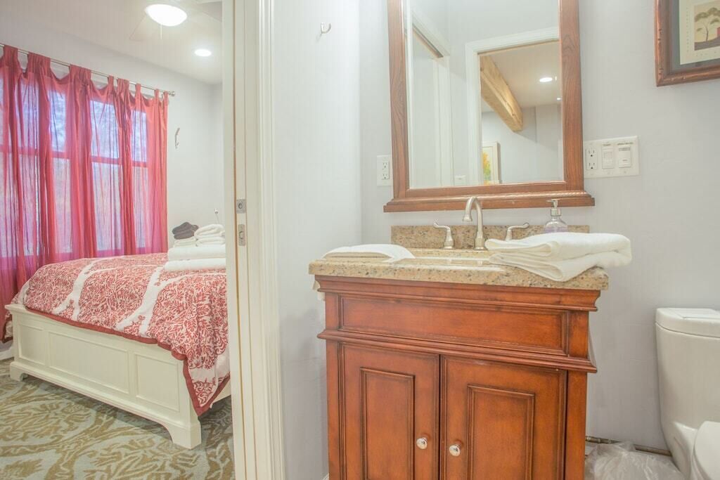 Une chambre avec un lit, une salle de bain avec un lavabo et un miroir, et des toilettes.