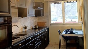 Une cuisine avec des meubles de couleur sombre, une cuisinière et une fenêtre donnant sur des arbres.