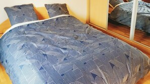 Une chambre à coucher avec un lit, un miroir et un luminaire suspendu.