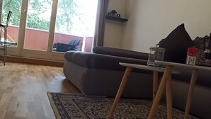 Un salon avec un canapé gris, une petite table sur laquelle se trouve une boisson et un plancher en bois.