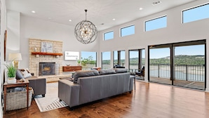 A spacious living room with a fireplace, a large gray sofa, and a view of the outdoors.
