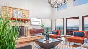 A modern living room with a fireplace, leather sofas, a coffee table, and large windows offering a view.