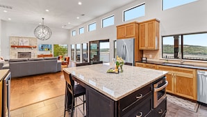 A spacious kitchen with a large island, wooden cabinets, and a stainless steel refrigerator.