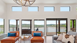 A spacious living area with leather sofas, a coffee table, and a view of a balcony with a railing.