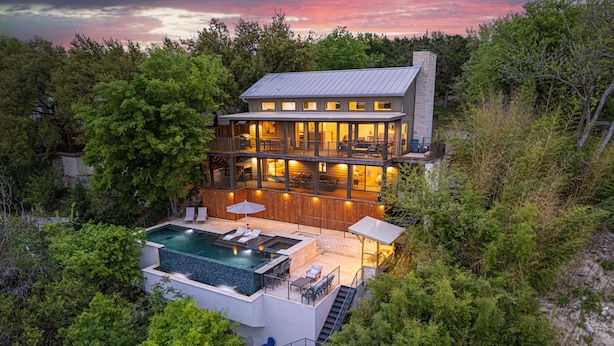 A modern two-story house with a large deck, a swimming pool, and a stone fireplace.