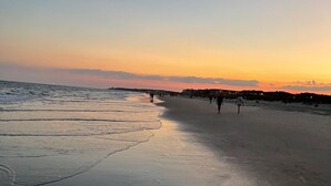 A beach at sunset with people walking along the shore. - Amazing Lagoon View, Largest Balcony in Fiddlers Cove!  5 min walk to the beach! (Hilton Head Island)