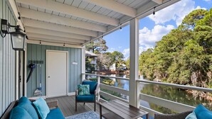 A covered outdoor area with wicker furniture, a view of a lake, and a door leading to the interior. - Amazing Lagoon View, Largest Balcony in Fiddlers Cove!  5 min walk to the beach! (Hilton Head Island)