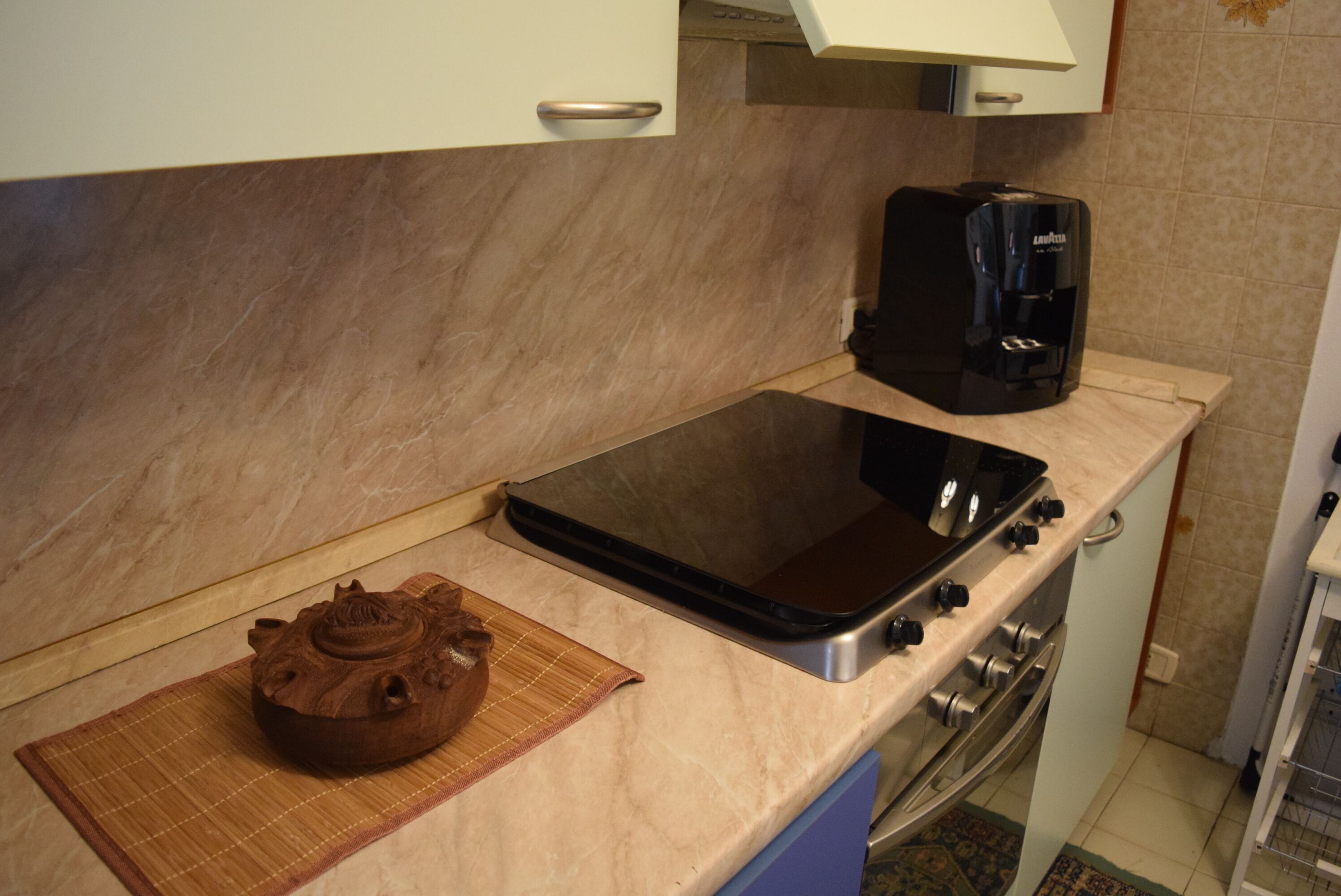 Eine Küche mit Herd, Kaffeemaschine und einem dekorativen Topf auf der Arbeitsplatte.