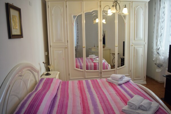 A bedroom with a bed, a wardrobe, and a mirror.