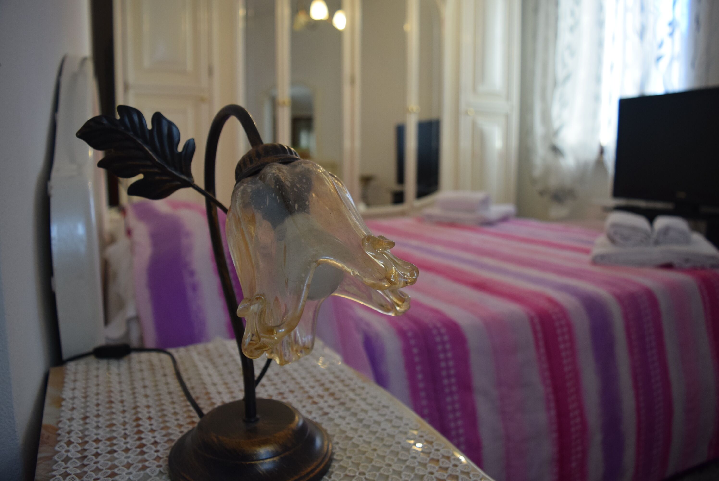 Une pièce avec un lit, un objet décoratif en verre posé sur une table et un téléviseur dans un coin.