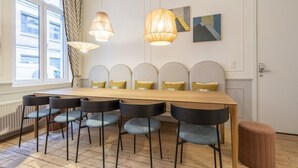 Een eetgedeelte met een lange houten tafel, zes stoelen en twee hangende hanglampen.