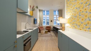 Een moderne keuken met teal kastjes, een centraal eiland en een eethoek met twee stoelen en een tafel.