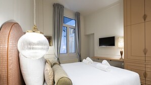 Een hotelkamer met een groot bed, een televisie, een bureau en een kledingkast.