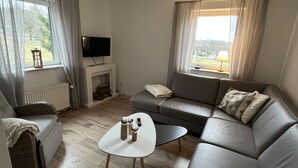 Ett modernt vardagsrum med en grå soffa, ett vitt soffbord och en tv som står på ett tv-bord.