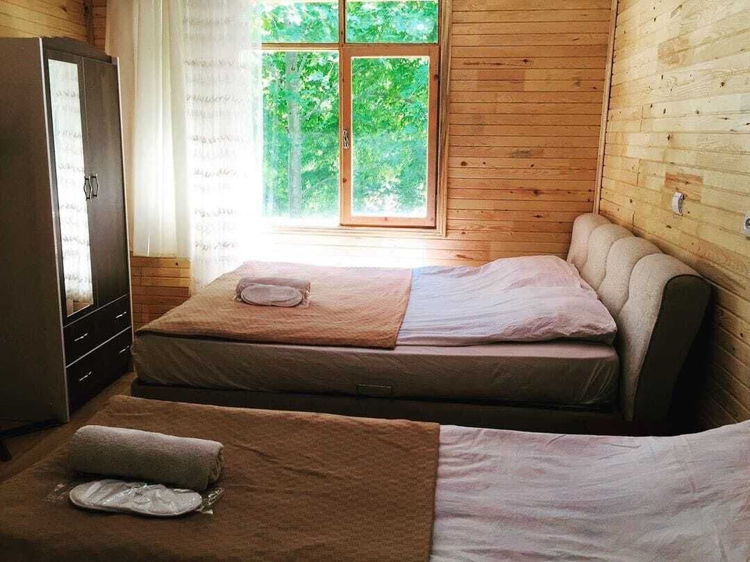 Une chambre avec deux lits, une armoire et une fenêtre donnant sur un paysage verdoyant.